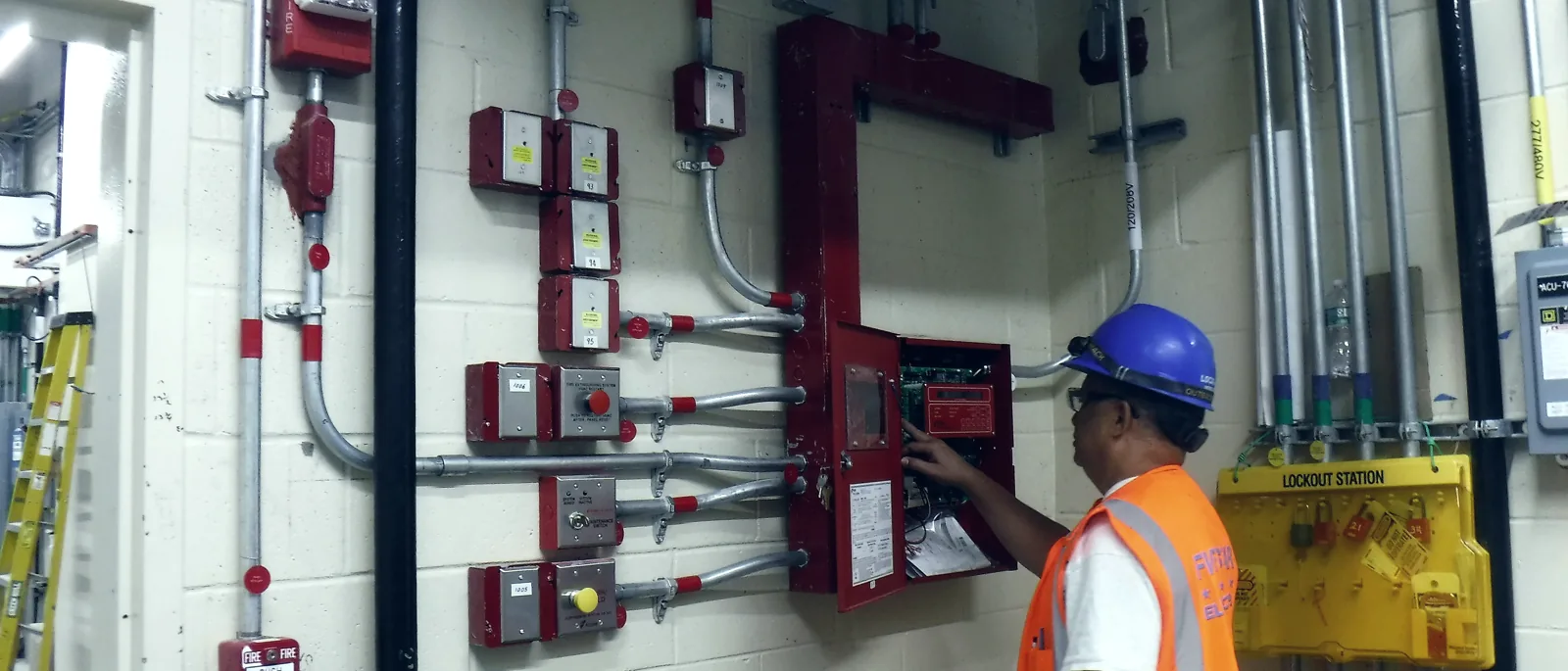 An engineer testing a fire alarm control panel in a plant room