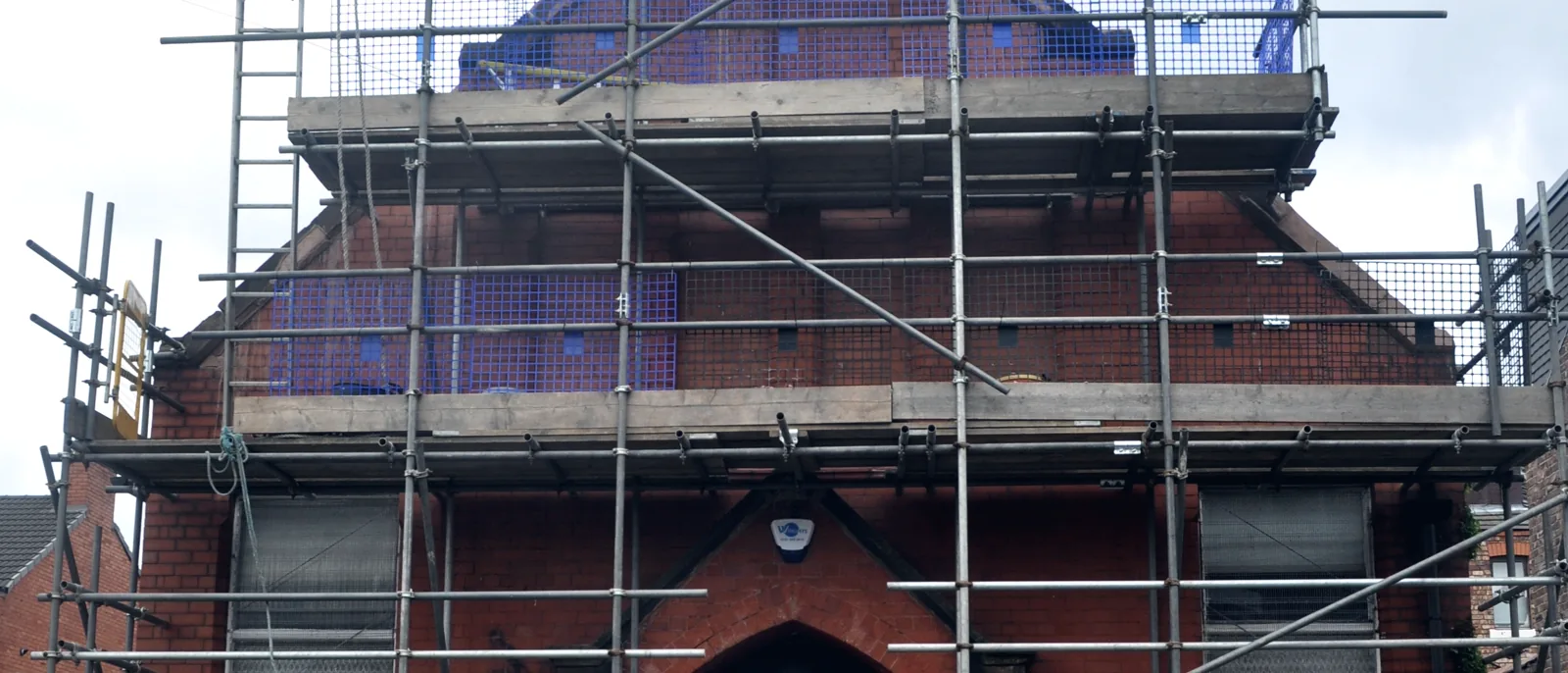 A brick hall wrapped in scaffolding during remediation works